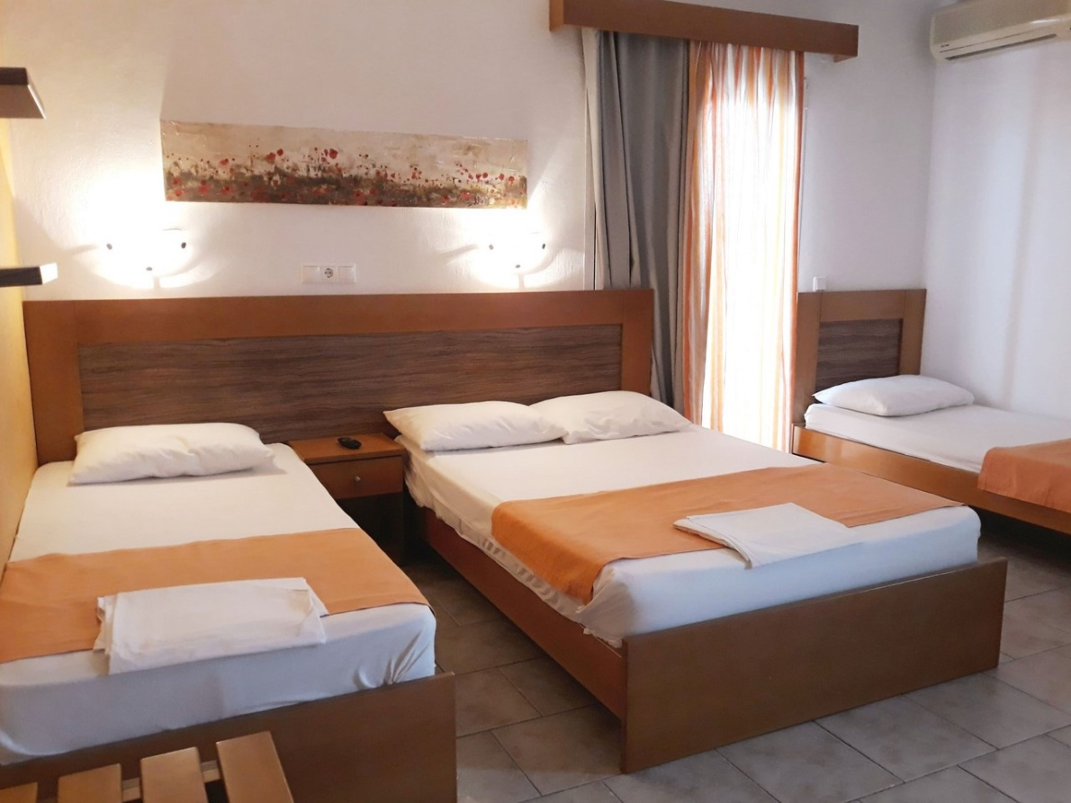 Bright room at Vasila Rooms with a double bed and single beds